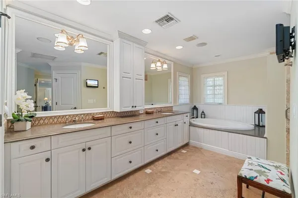 a spacious bathroom with a granite countertop double vanity sink a mirror and a bathtub