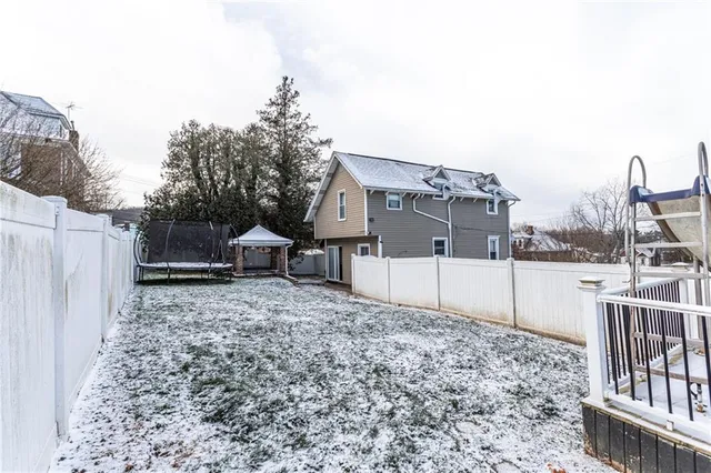 a view of a backyard with large trees and wooden fence