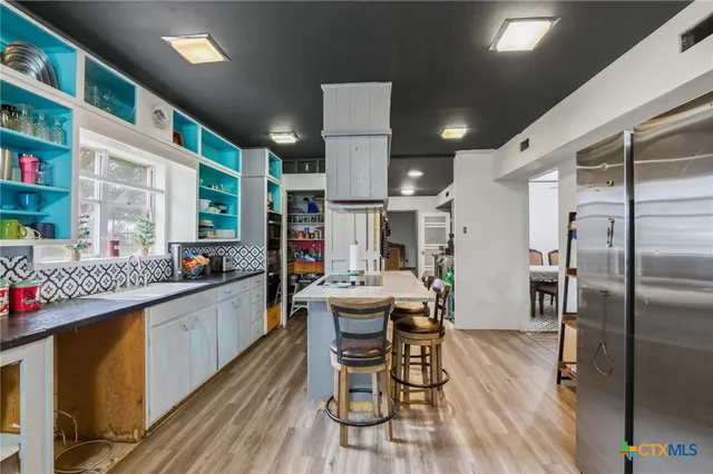 a kitchen with stainless steel appliances kitchen island granite countertop a table chairs in it and wooden floors