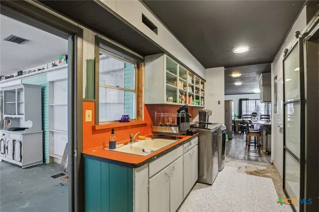 a kitchen that has a lot of cabinets a sink and appliances in it