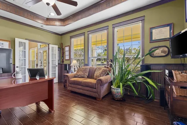 a living room with furniture potted plant floor to ceiling windows and a flat screen tv