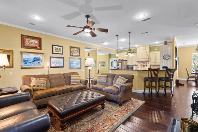 a living room with furniture kitchen view and a wooden floor