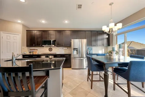 a kitchen with stainless steel appliances a dining table chairs stove refrigerator and microwave
