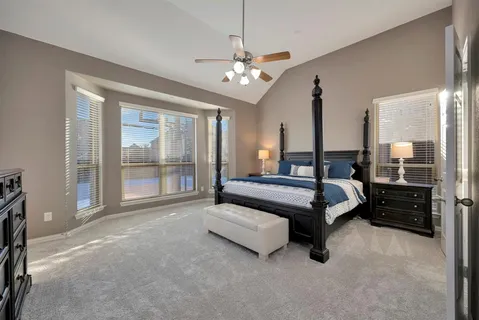 a spacious bedroom with a bed a chandelier and large window