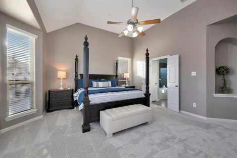 a spacious bedroom with a bed a couch and large window