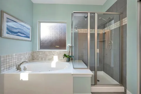 a bathroom with a granite countertop sink a mirror a bathtub and shower