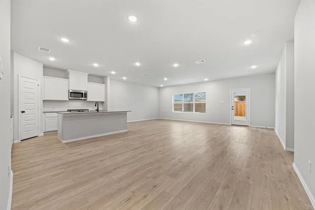 a view of kitchen with stainless steel appliances granite countertop a stove a sink and white cabinets