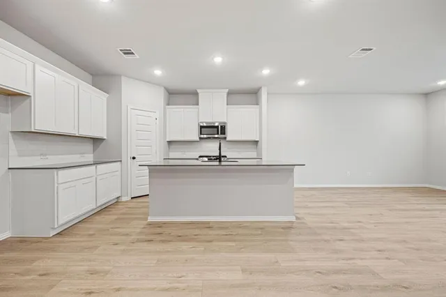 a kitchen with stainless steel appliances white cabinets a sink and a stove