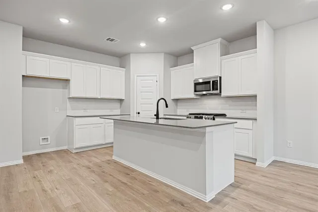 a kitchen with stainless steel appliances granite countertop white cabinets a sink and dishwasher