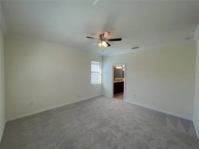a view of a white house with table and chairs potted plants and palm trees