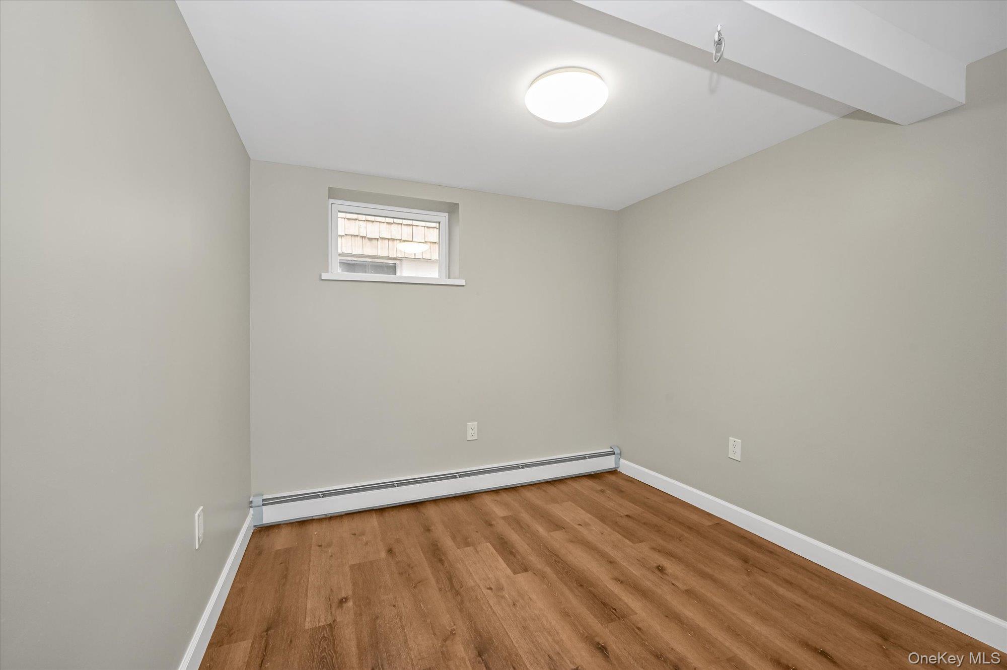 64-39 58th Road Queens, NY 11378 - Photo 13 of 19 a view of an empty room with wooden floor and a window