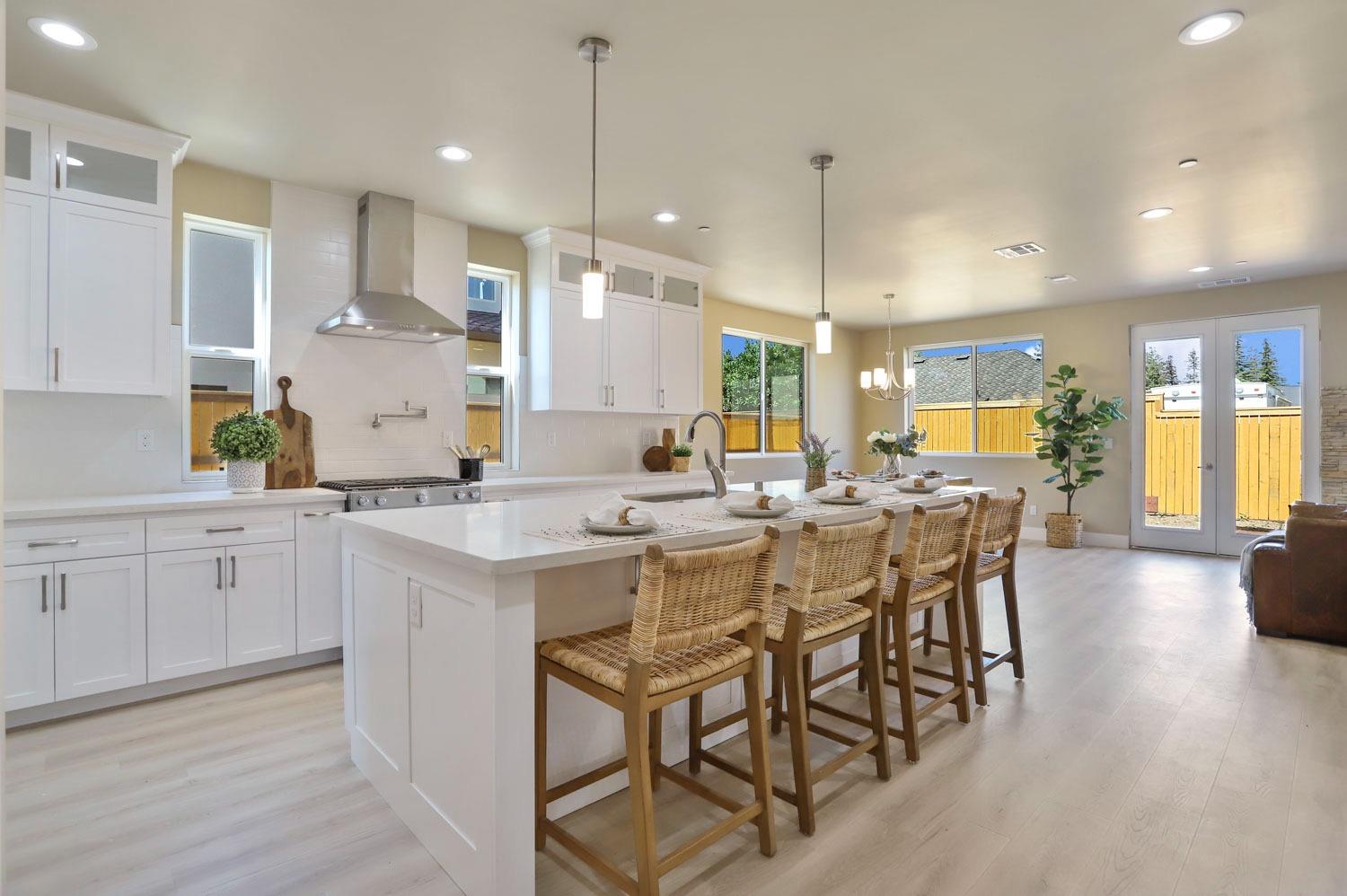 a kitchen with a dining table chairs wooden floor cabinets and appliances