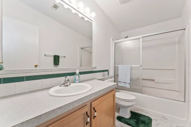 a bathroom with a granite countertop sink toilet a mirror and shower