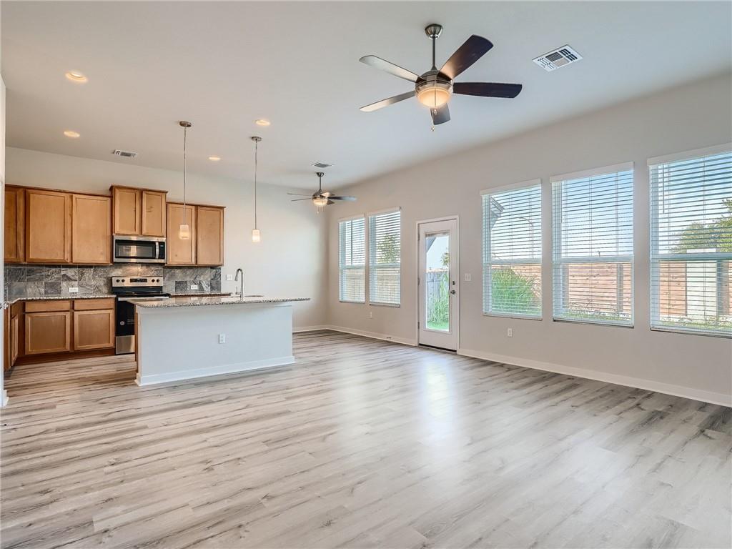1309 Showbox Street, Unit 6 Pflugerville, TX 78660 - Photo 6 of 24 a large kitchen with stainless steel appliances granite countertop a stove a sink dishwasher and a large refrigerator with wooden floor