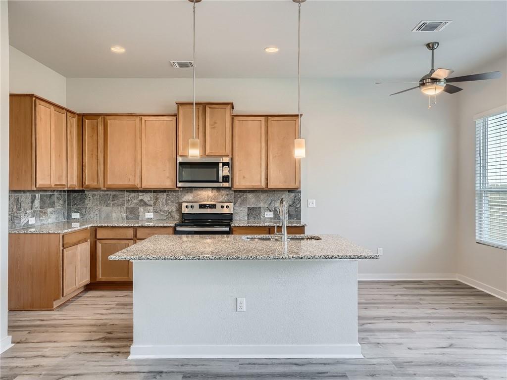 1309 Showbox Street, Unit 6 Pflugerville, TX 78660 - Photo 7 of 24 a kitchen with stainless steel appliances granite countertop a sink a stove and a wooden floors