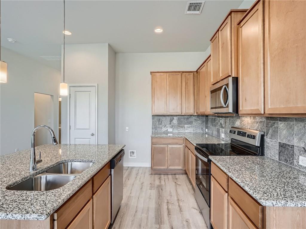 1309 Showbox Street, Unit 6 Pflugerville, TX 78660 - Photo 8 of 24 a kitchen with stainless steel appliances granite countertop a sink stove and cabinets