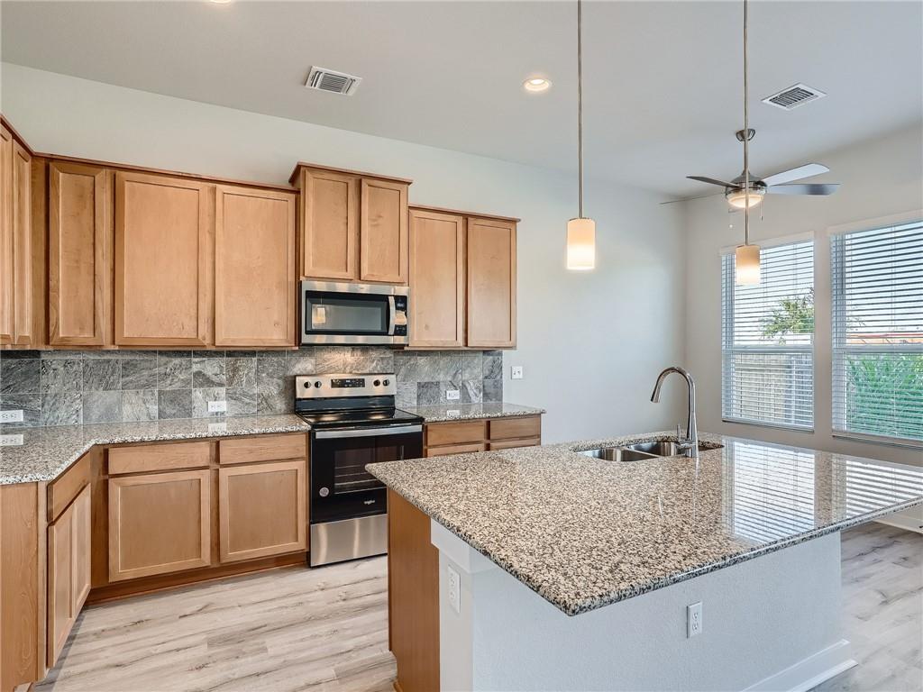 1309 Showbox Street, Unit 6 Pflugerville, TX 78660 - Photo 9 of 24 a kitchen with stainless steel appliances granite countertop a sink a stove and a microwave