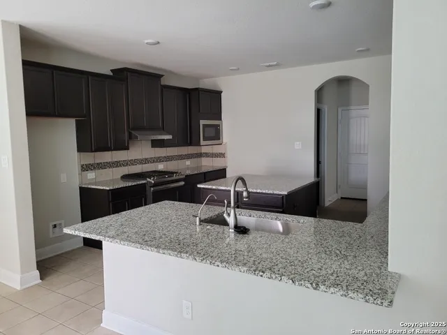 a kitchen with kitchen island granite countertop a sink a stove and refrigerator