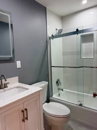 a bathroom with a granite countertop sink toilet and shower