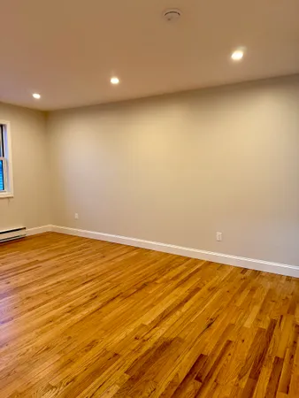 an empty room with wooden floor and natural light