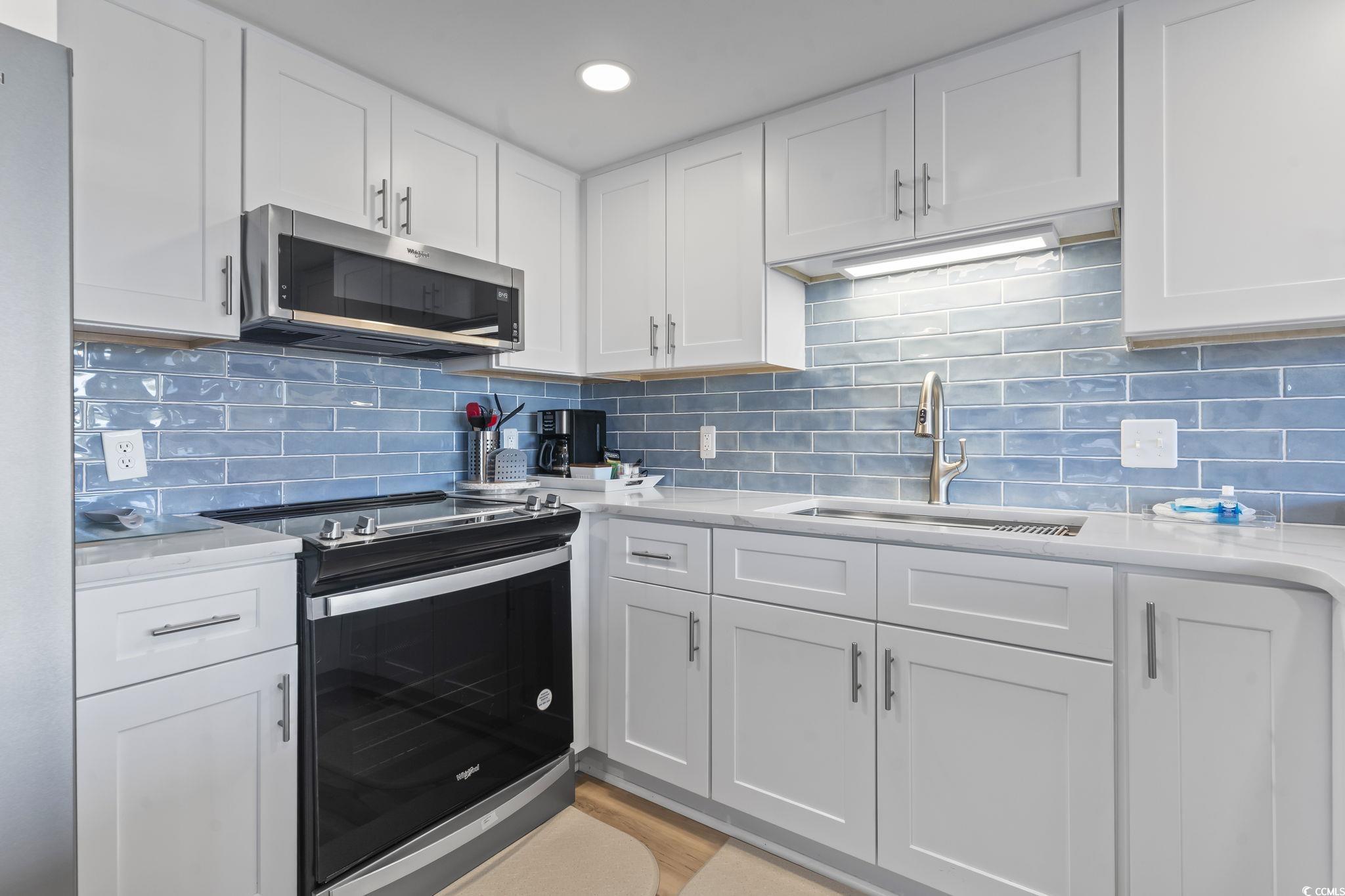 310 3rd Avenue North, Unit A2 Surfside Beach, SC 29575 - Photo 11 of 40 Kitchen with stainless steel appliances, white cabinets, and tasteful backsplash