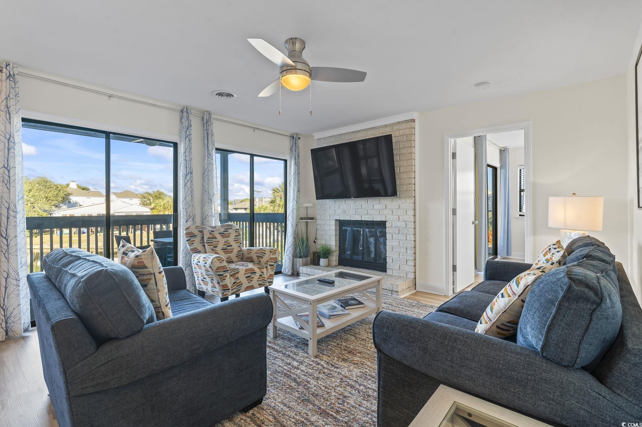 310 3rd Avenue North, Unit A2 Surfside Beach, SC 29575 - Photo 12 of 40 Living room featuring wood finished floors, a brick fireplace, and a ceiling fan