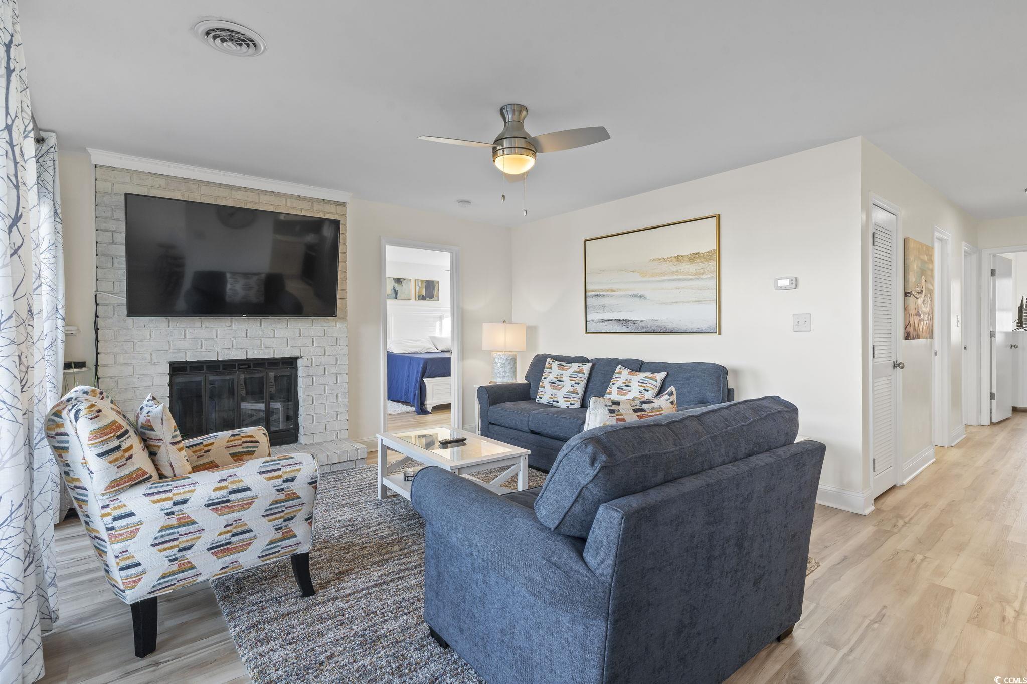 310 3rd Avenue North, Unit A2 Surfside Beach, SC 29575 - Photo 14 of 40 Living room featuring a fireplace, light wood-style floors, and ceiling fan