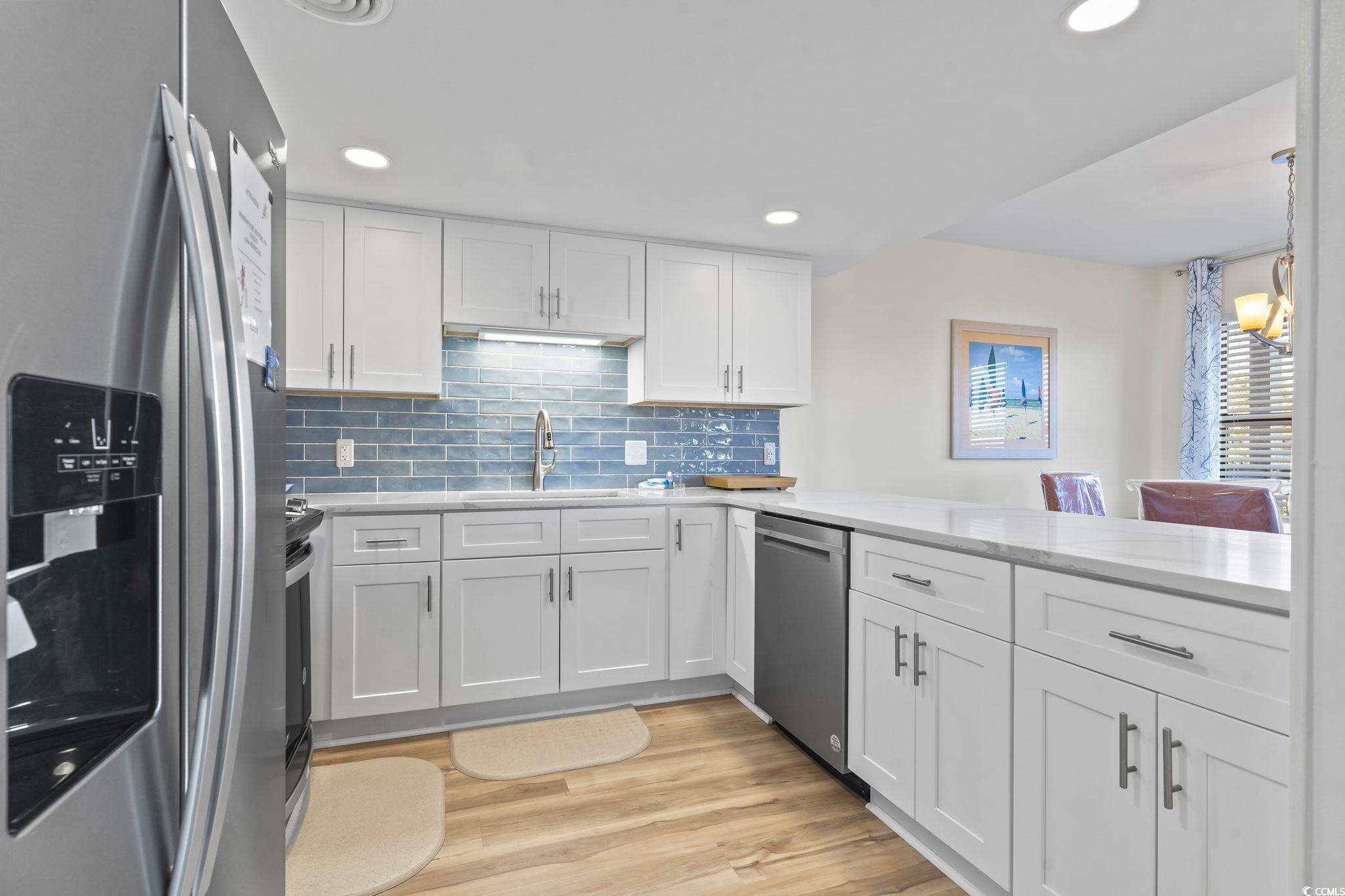 310 3rd Avenue North, Unit A2 Surfside Beach, SC 29575 - Photo 2 of 40 Kitchen featuring stainless steel appliances, white cabinets, tasteful backsplash, light wood-type flooring, and recessed lighting