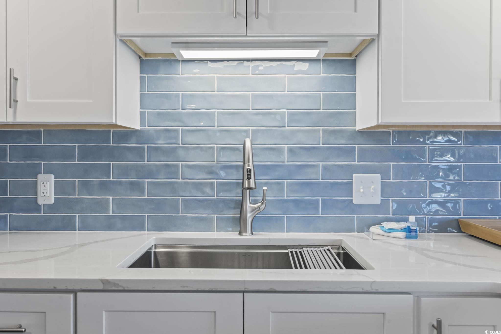 310 3rd Avenue North, Unit A2 Surfside Beach, SC 29575 - Photo 4 of 40 Kitchen view of light stone countertops, white cabinetry, and decorative backsplash