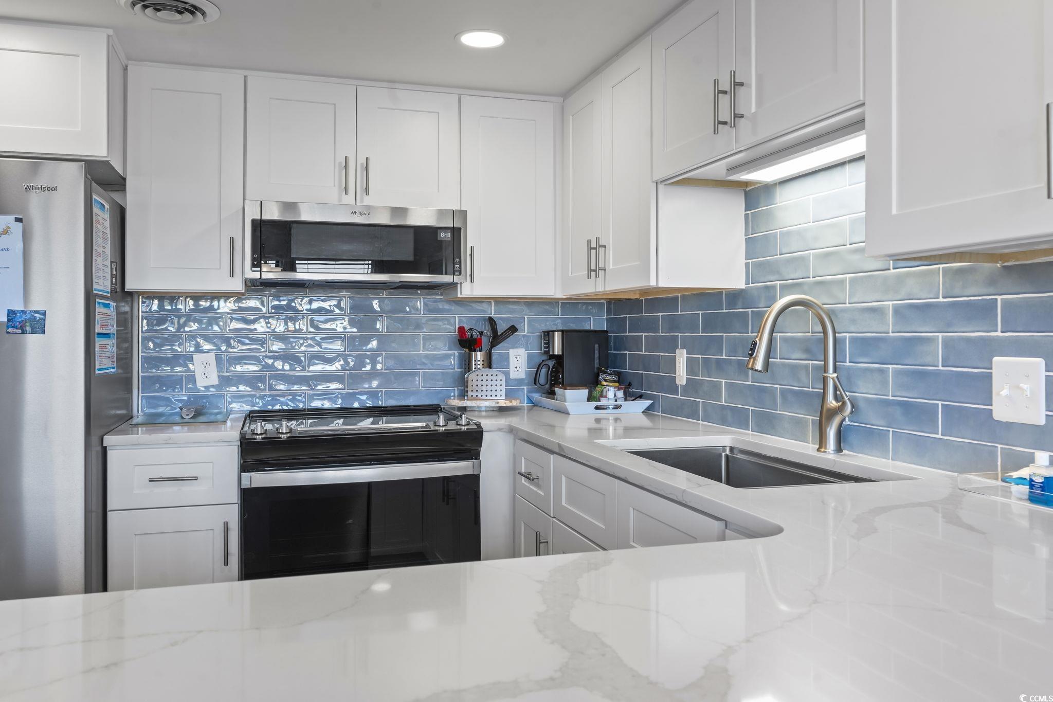 310 3rd Avenue North, Unit A2 Surfside Beach, SC 29575 - Photo 5 of 40 Kitchen with white cabinetry, stainless steel appliances, and light stone counters
