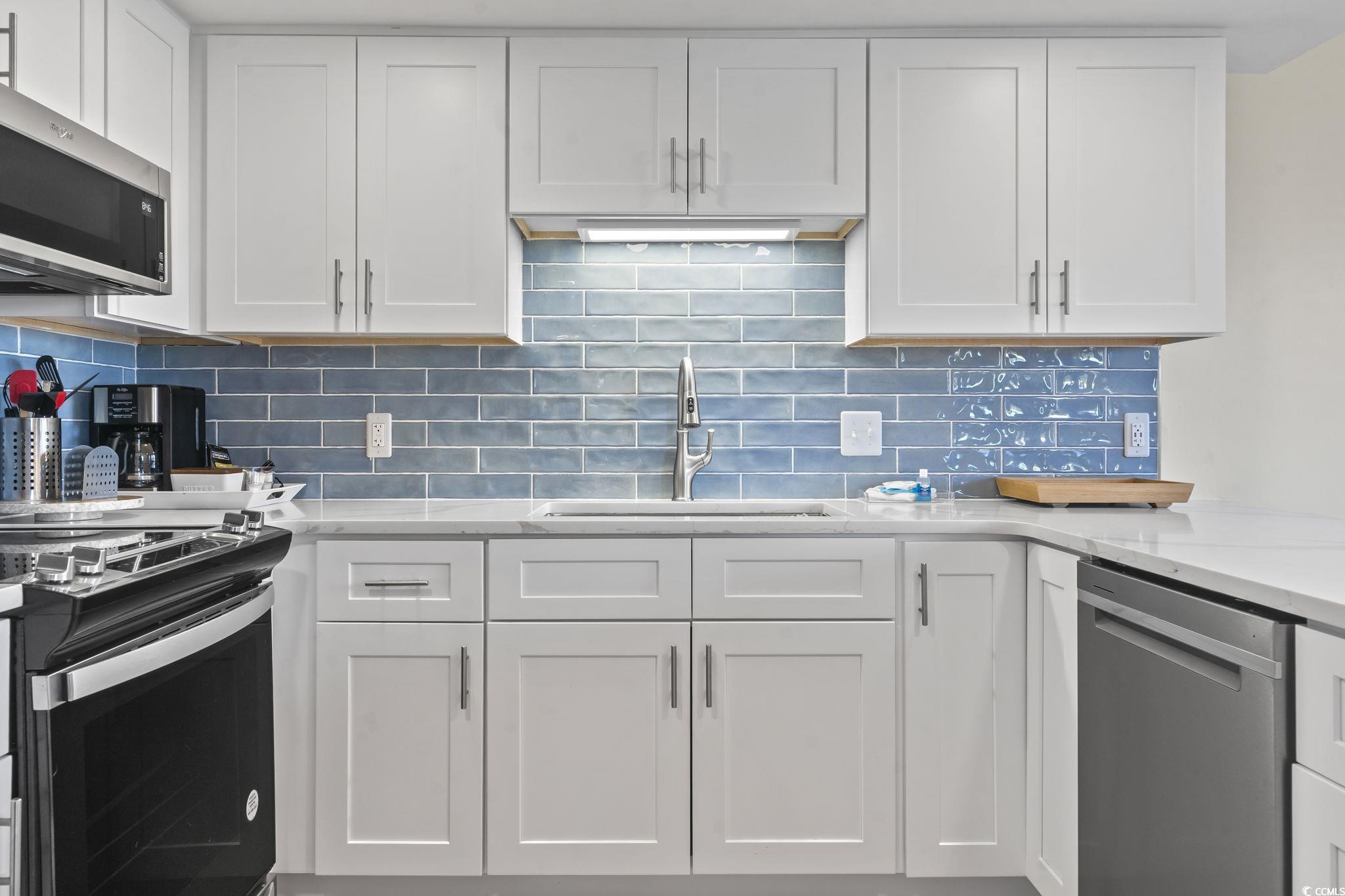 310 3rd Avenue North, Unit A2 Surfside Beach, SC 29575 - Photo 8 of 40 Kitchen with white cabinets, appliances with stainless steel finishes, light stone countertops, and tasteful backsplash
