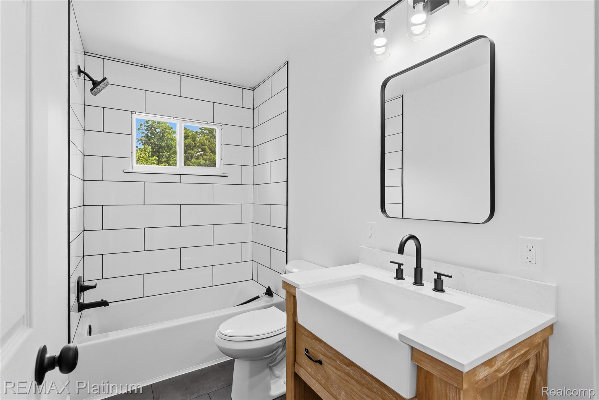 8370 West Rolston Road Linden, MI 48451 - Photo 23 of 36 Modern bathroom featuring a farmhouse-style vanity with an integrated sink, matte black fixtures, and a rectangular framed mirror