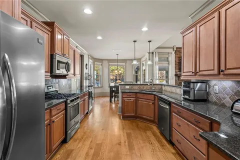 a kitchen with stainless steel appliances granite countertop a stove top oven a sink dishwasher a refrigerator and cabinets with wooden floor