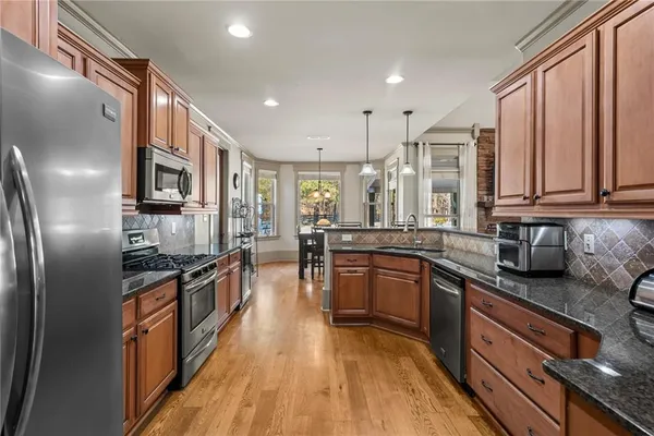 a kitchen with stainless steel appliances granite countertop a stove top oven a sink dishwasher a refrigerator and cabinets with wooden floor