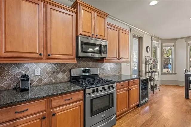 a kitchen with stainless steel appliances granite countertop a stove a sink and a microwave