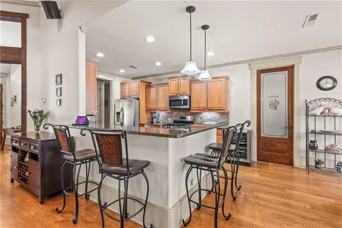 a kitchen with stainless steel appliances kitchen island granite countertop a table chairs and a refrigerator