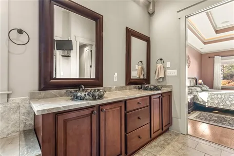 a spacious bathroom with a granite countertop sink a mirror a bathtub and shower