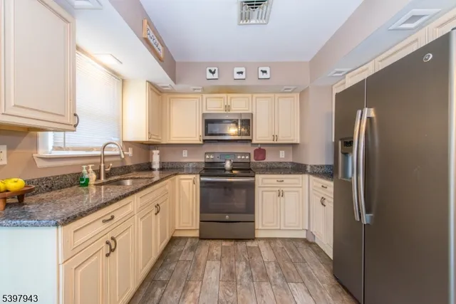 a kitchen with granite countertop a refrigerator stove top oven and sink