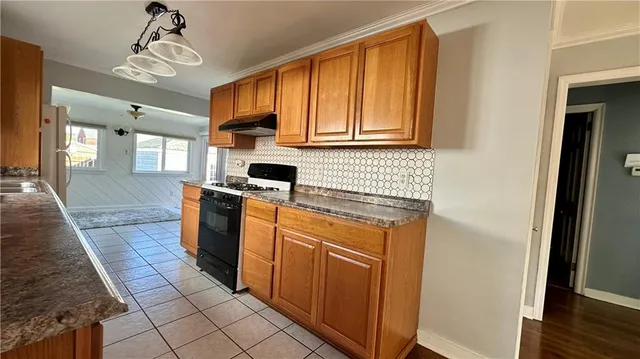 a kitchen with stainless steel appliances granite countertop a refrigerator a sink dishwasher and wooden cabinets with wooden floor