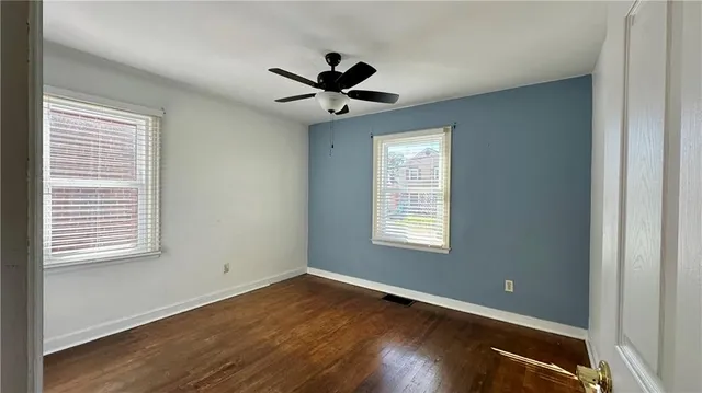 a view of empty room with wooden floor and fan