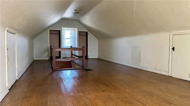 a view of an empty room with wooden floor and a closet