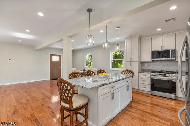 a kitchen with a stove a sink a kitchen island with chairs and wooden floor
