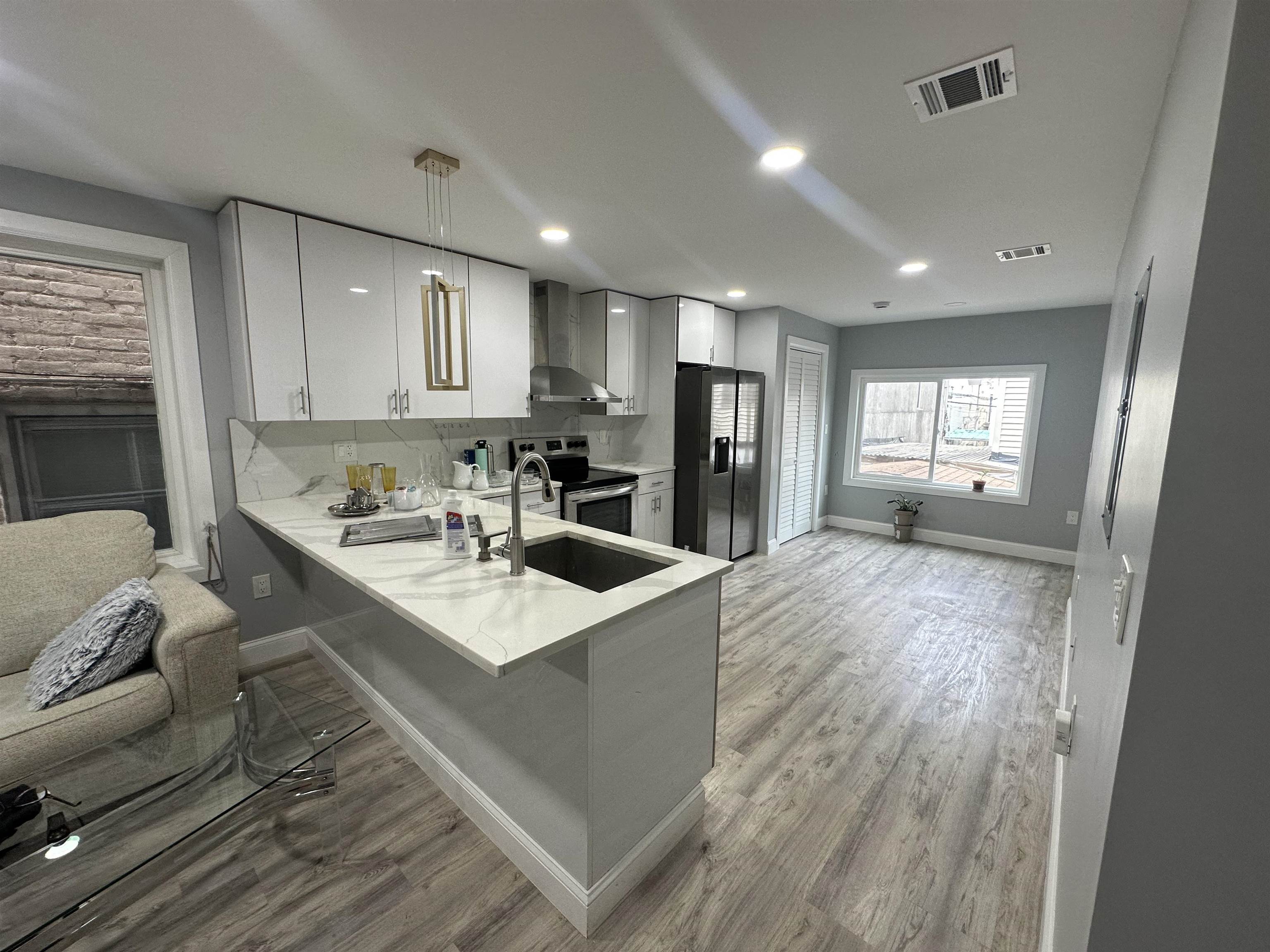 a large white kitchen with a refrigerator a stove a sink dishwasher and a dining table with wooden floor