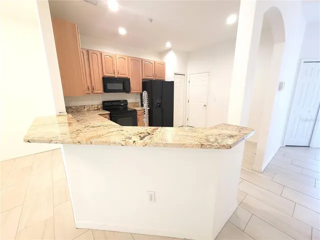 a view of kitchen with granite countertop sink and refrigerator