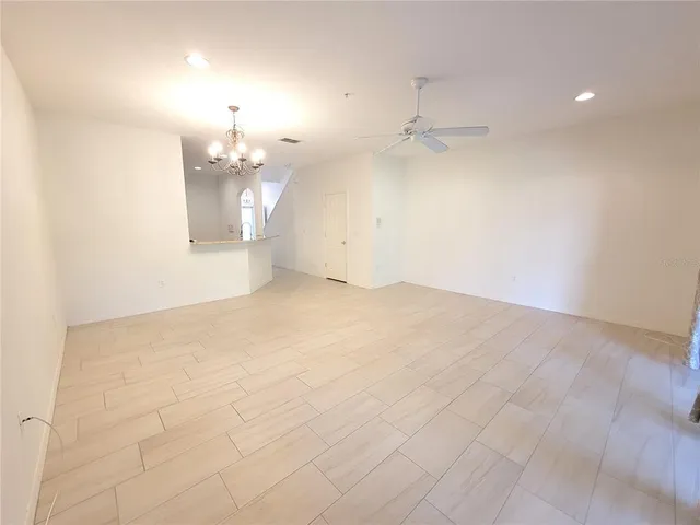 an empty room with kitchen and chandelier fan
