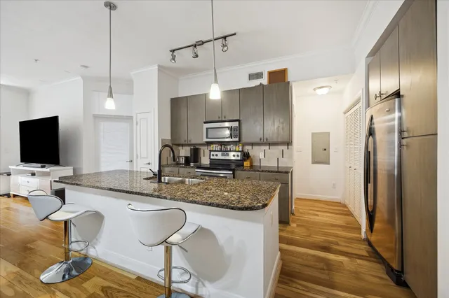 a kitchen with granite countertop kitchen island stainless steel appliances a sink stove and refrigerator