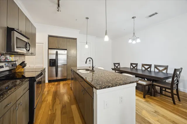 a kitchen with stainless steel appliances granite countertop a sink a stove and a wooden floors