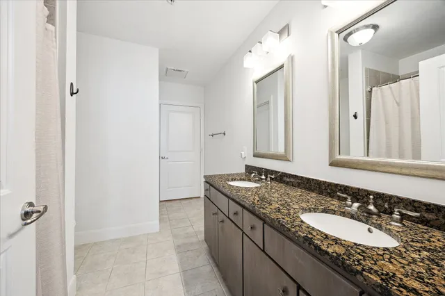 a bathroom with a granite countertop double vanity sink and mirror