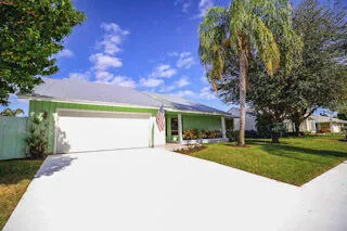 a front view of a house with a garden and trees