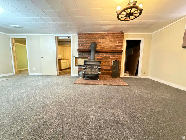 156 D Street Helper, UT 84526 - Photo 20 of 24 Unfurnished living room with carpet flooring, ornamental molding, and a wood stove